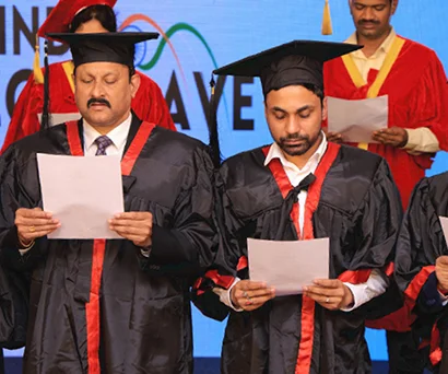 Dr. Sabyasachi Saha in academic robes reading from a sheet during the felicitation ceremony at India Conclave 2025, Chennai