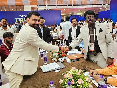 Dr. Sabyasachi Saha shaking hands with a delegate at a meeting table, Tripura Business Conclave 2026